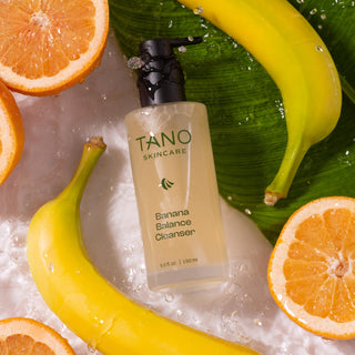 Tano Skincare Banana Balance Cleanser bottle with bananas and grapefruit on a banana leaf background