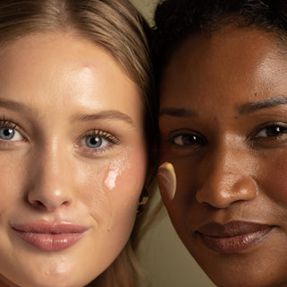 Two women with close-up faces, one with blonde hair and blue eyes, the other with dark skin and brown eyes, against a neutral background. Tano Skincare products on cheeks.
