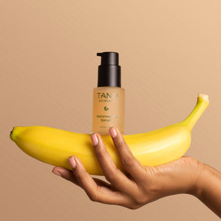 Hand balancing Tano Skincare Reformulate Serum on top of a banana.