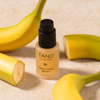 Tano Skincare Reformulate Serum bottle with bananas on a porous stone background