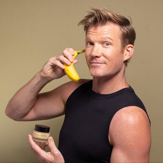 Person holding a banana and a container, posing against a plain background